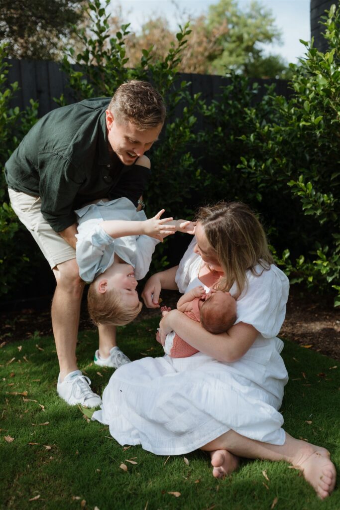 Family playing on grass in their backyard in Beaumaris while having their photos taken. 

