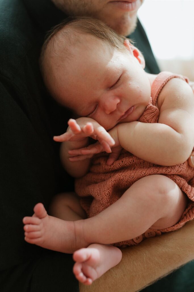 Close up of newborn baby asleep on dad's chest. 
